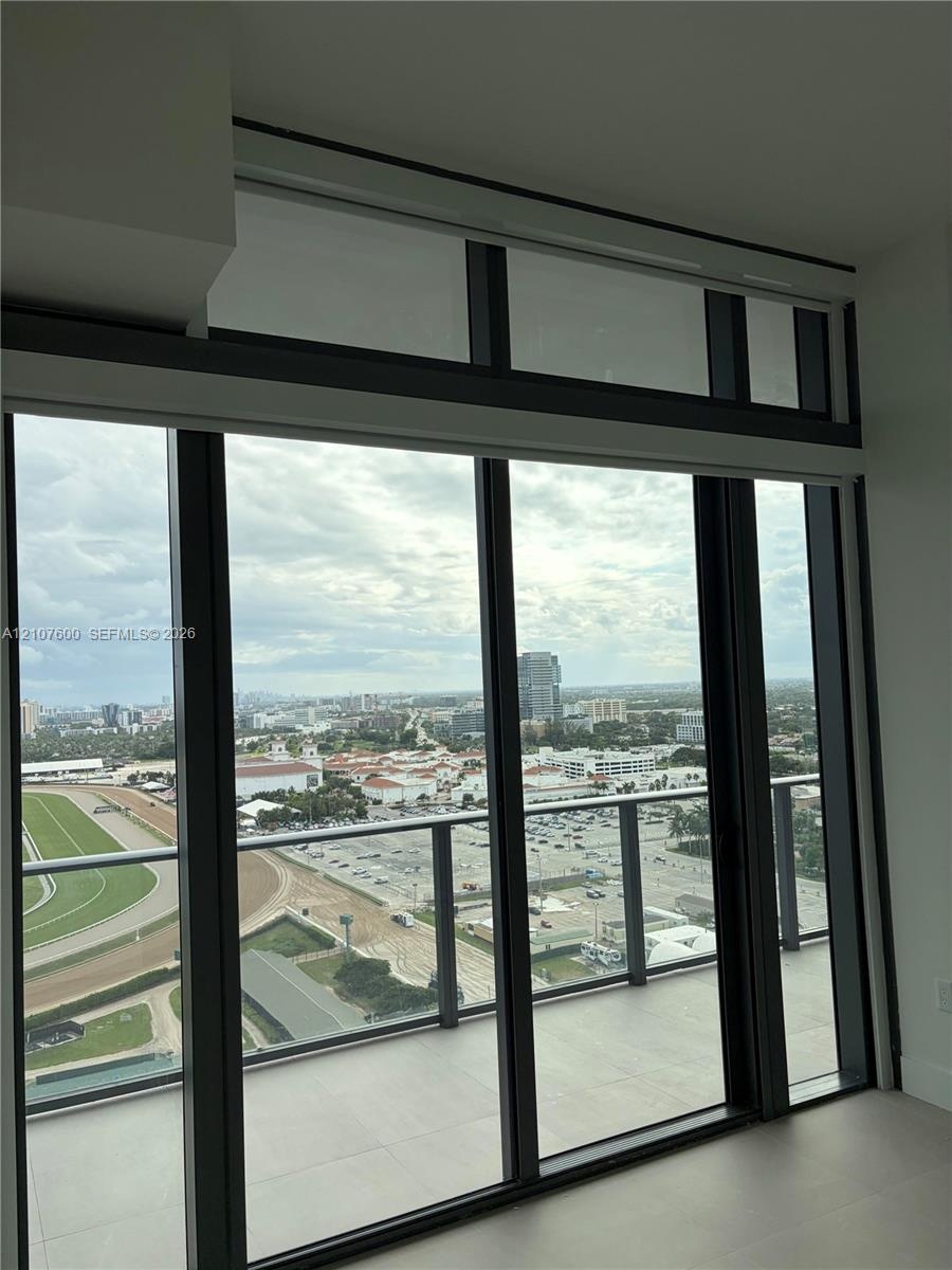Floor-to-ceiling windows with black metal frames, integrated transom windows, and a private balcony featuring a glass panel railing
