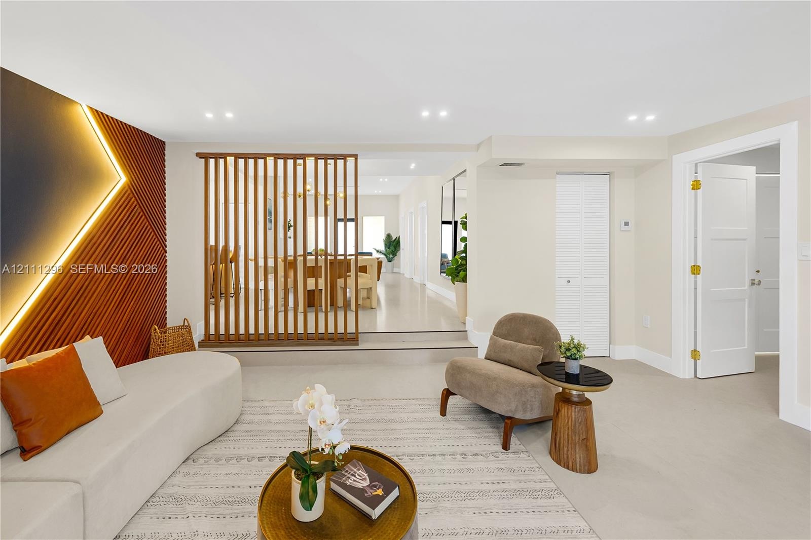 Living area featuring a vertical-slat wood room divider, textured accent wall with recessed lighting, smooth-finish flooring, and recessed ceiling lig