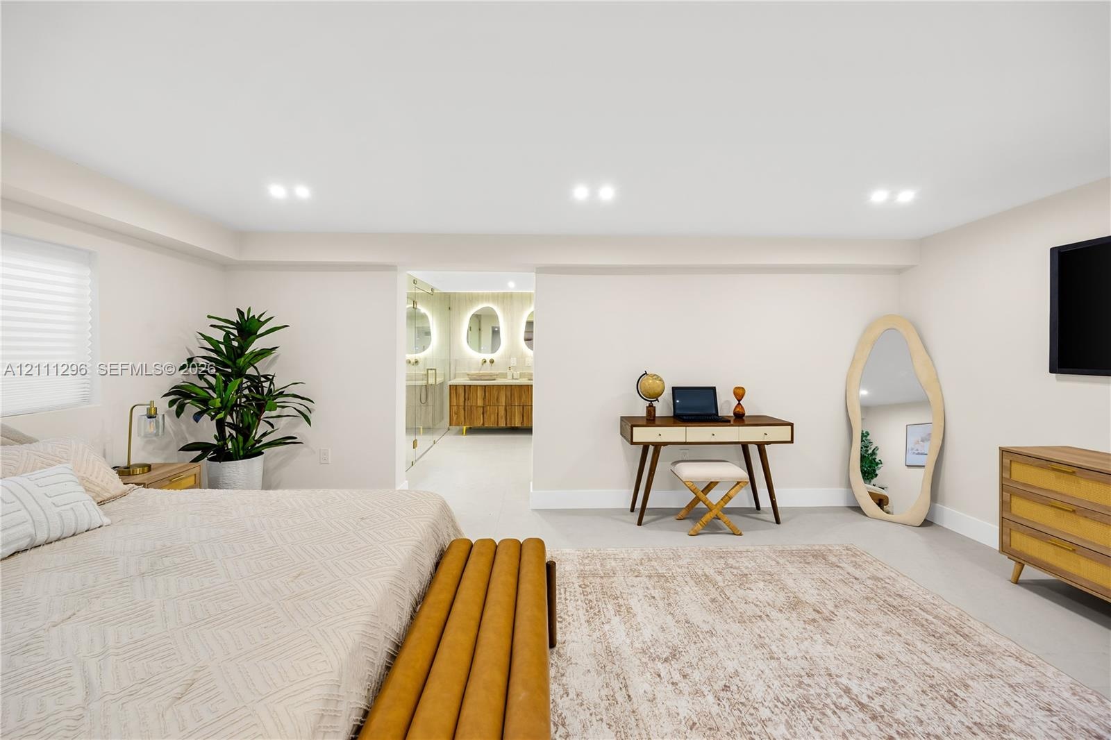 Neutral-toned room featuring recessed ceiling lighting, light-colored tile flooring, and integrated access to a bathroom with a double-sink vanity and
