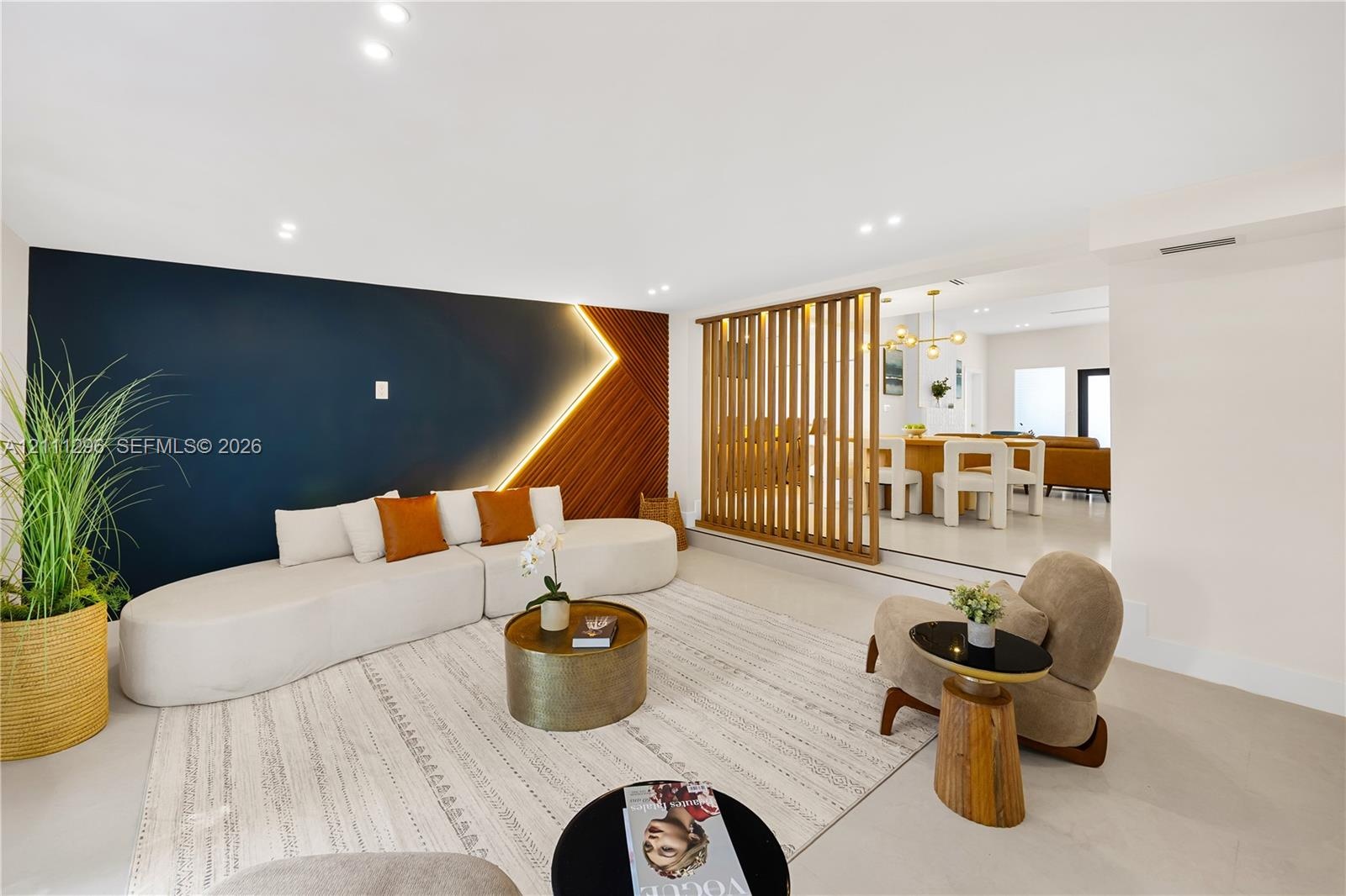 Living area featuring a floor-to-ceiling wooden slat partition, recessed lighting, and a dual-tone accent wall with integrated LED strip lighting