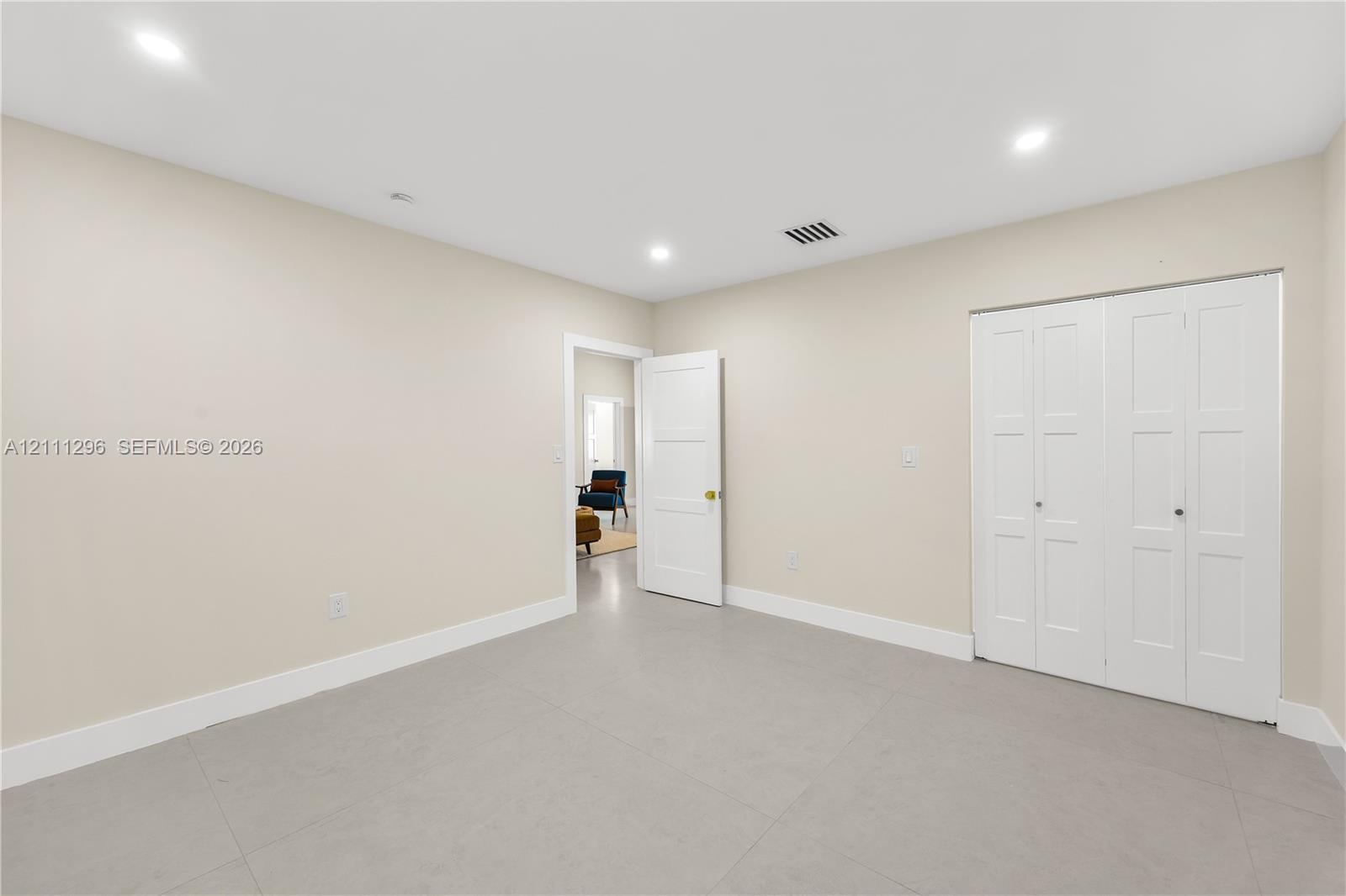 Neutral-toned room featuring recessed lighting, smooth-finish flooring, and a multi-panel door closet with white finish