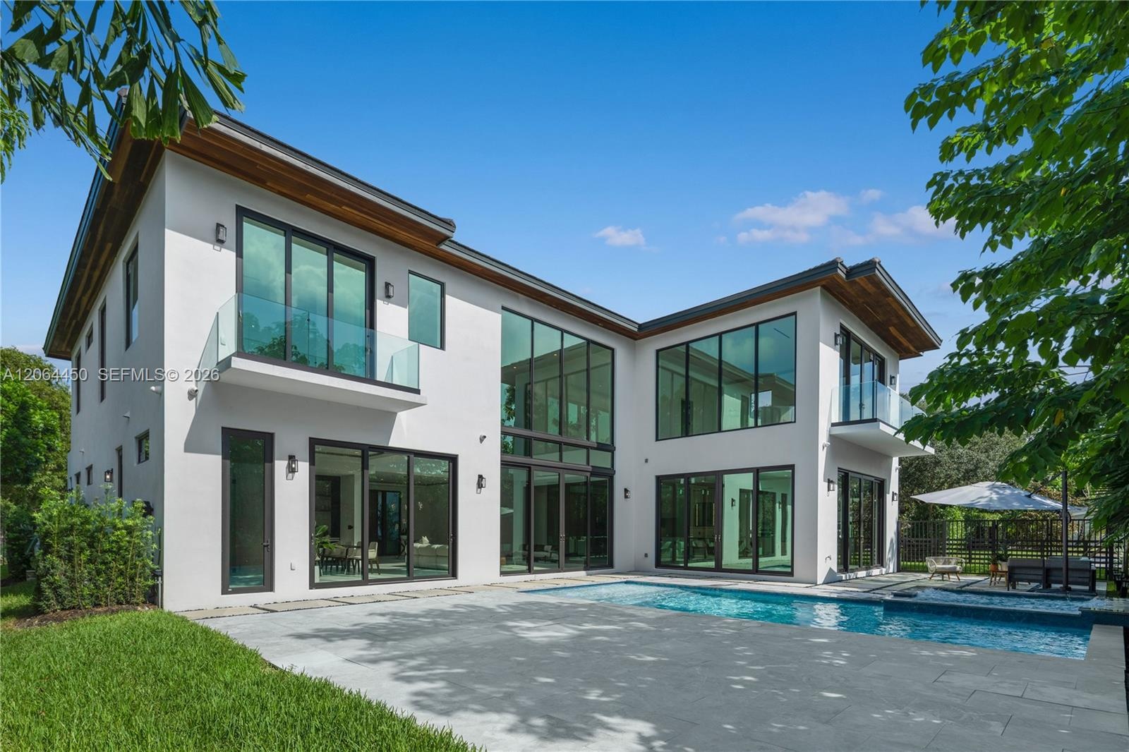 Backyard view of the home, pool deck, and landscaped lawn