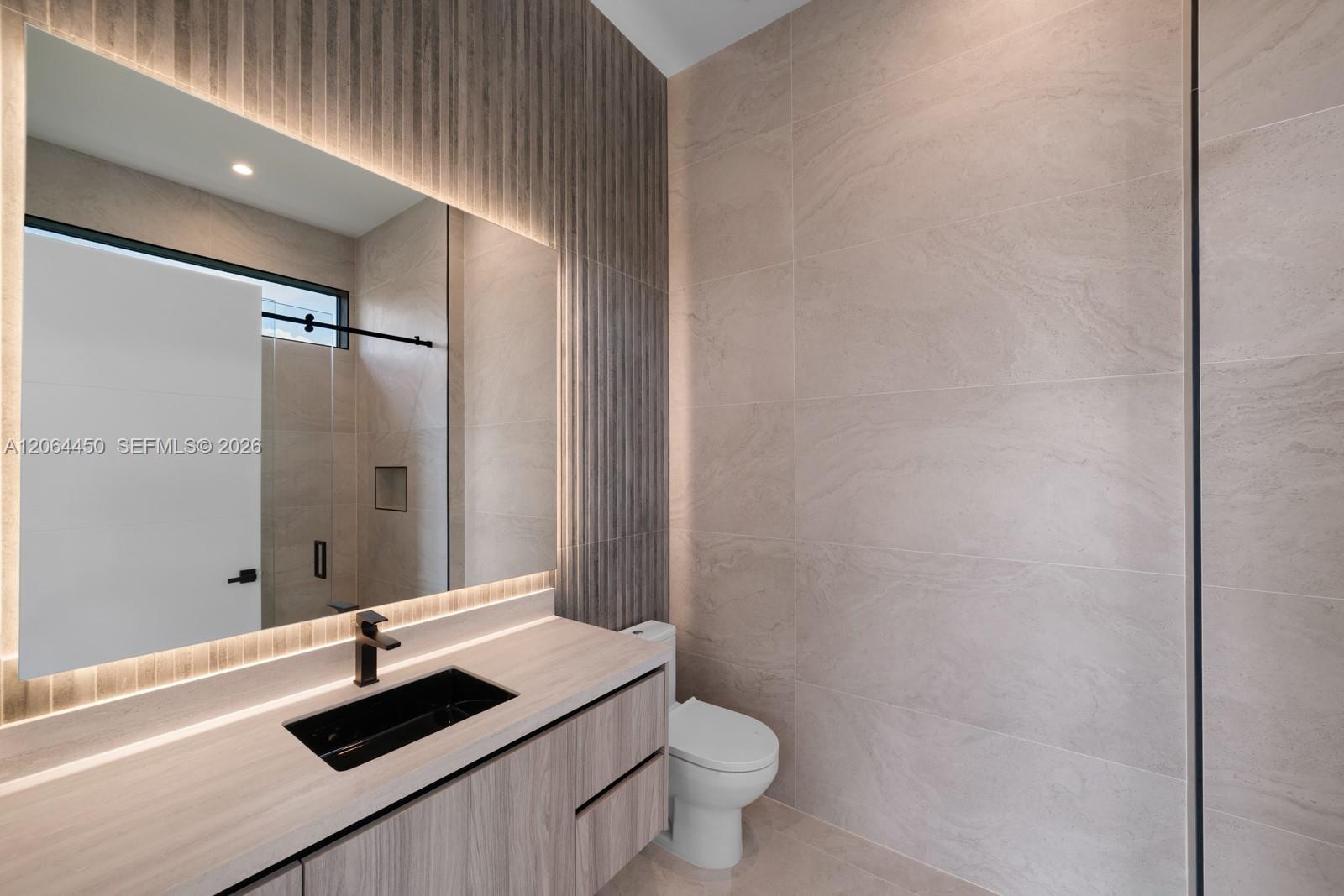 Floating vanity with integrated countertop, rectangular black vessel sink, matte black faucet, and vertical wood-texture wall paneling with recessed L
