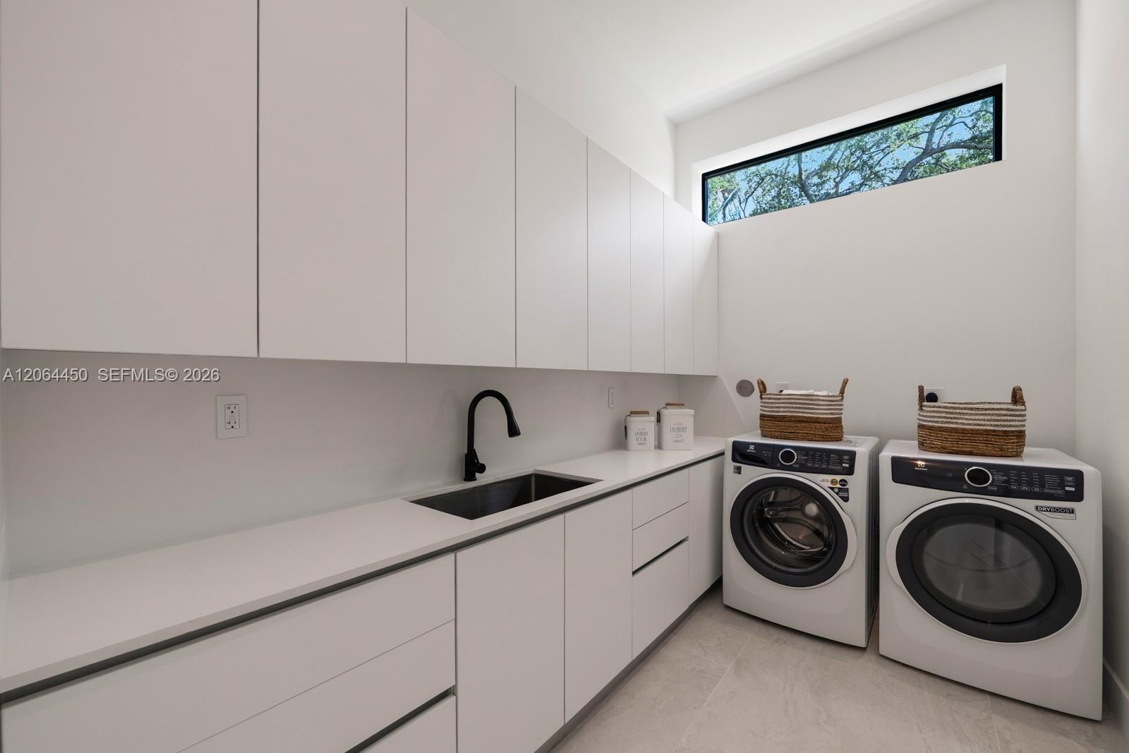 Minimalist utility room featuring floor-to-ceiling white cabinetry, a composite countertop with an integrated basin, a matte black gooseneck faucet, a