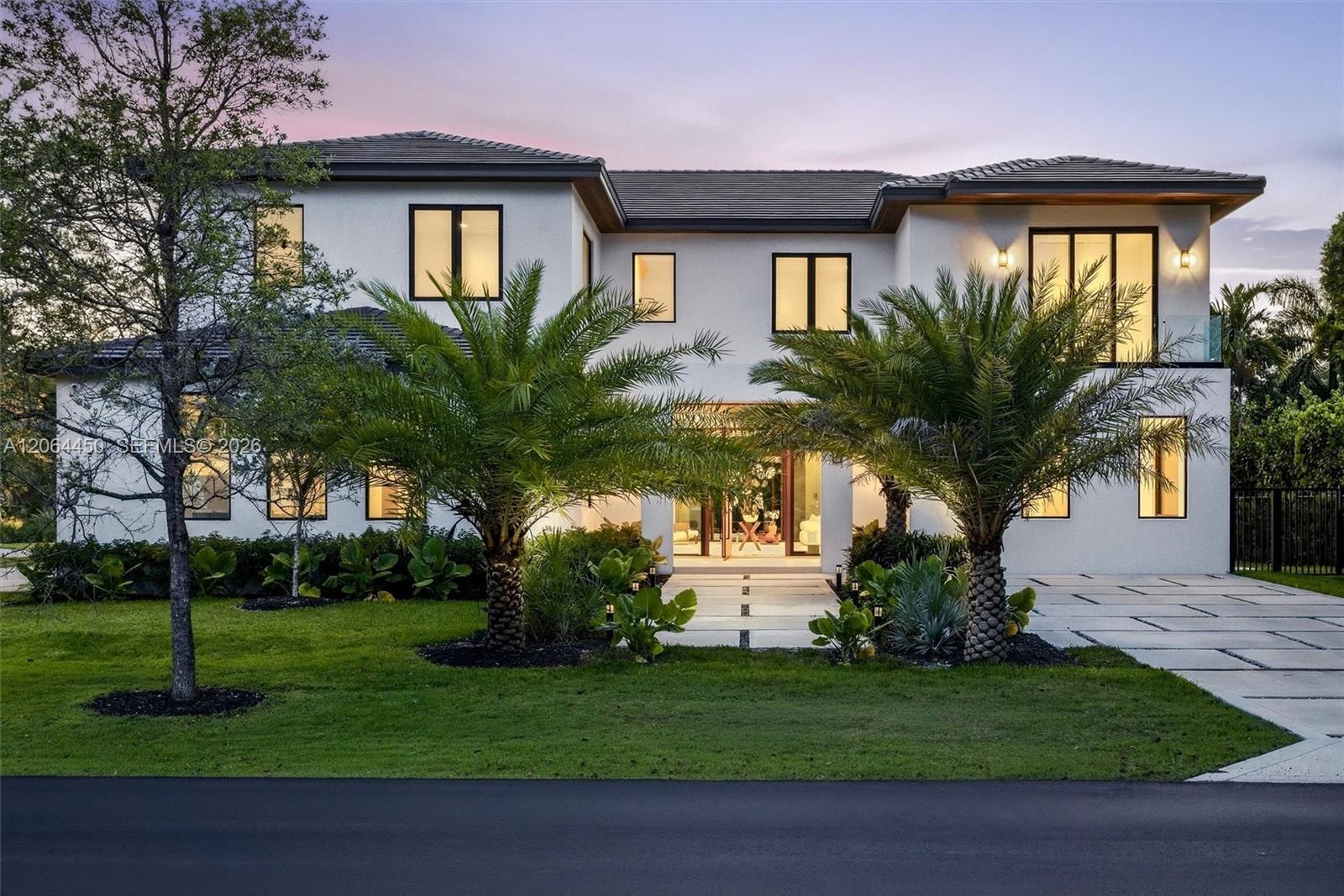 Two-story contemporary exterior featuring a smooth stucco finish, dark-framed multi-pane windows, a tiled roof, and a paved geometric driveway