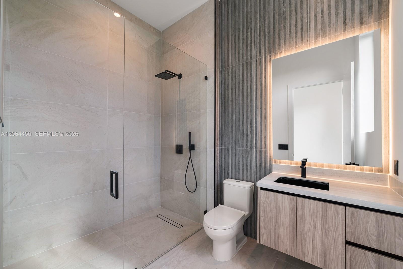 Walk-in shower with a glass enclosure and rain-style showerhead, floating vanity with wood-finish cabinetry, countertop vessel sink, matte black hardw