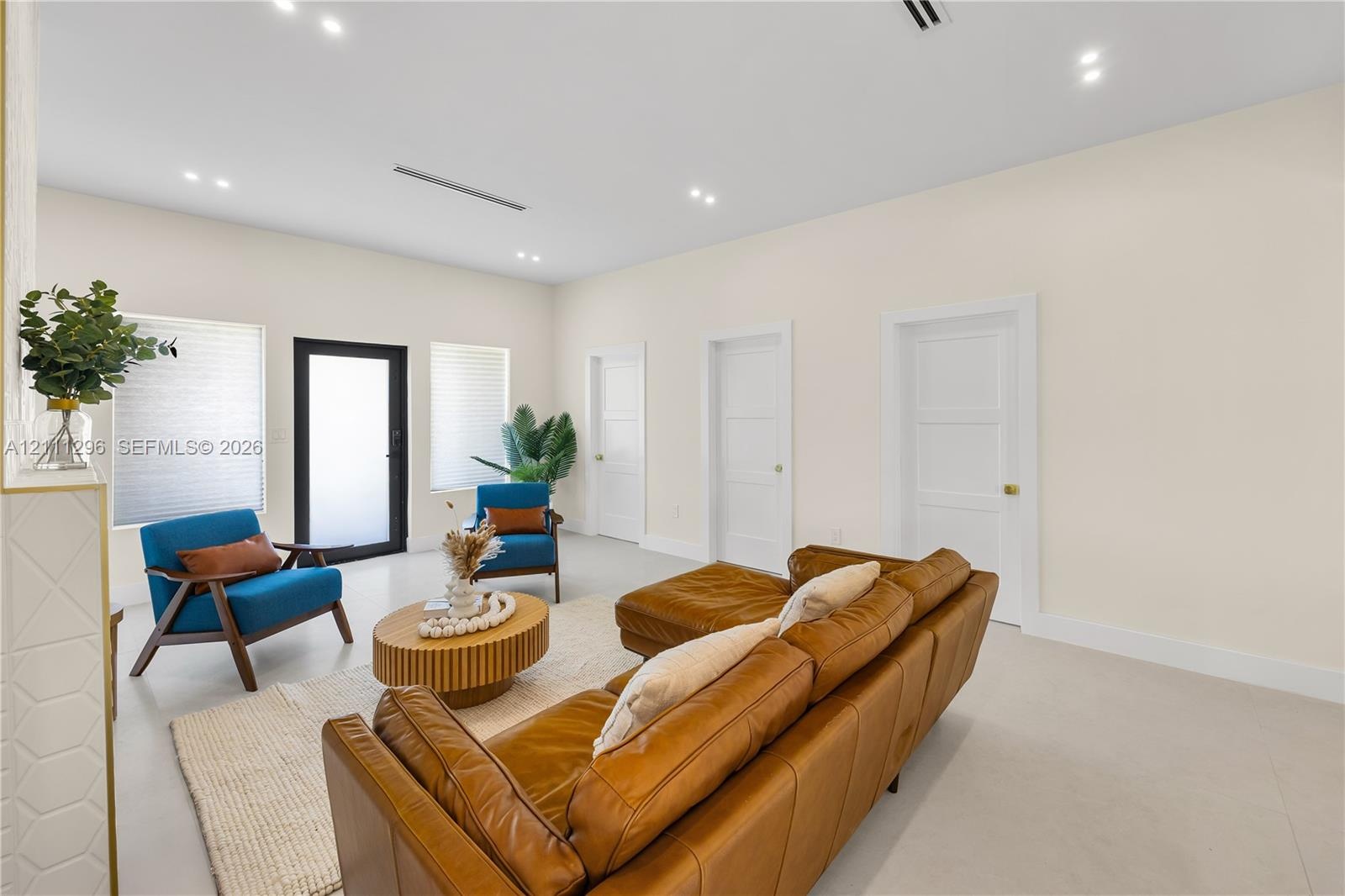 Neutral-toned interior featuring smooth-finish flooring, recessed ceiling lighting, three paneled interior doors, and a black-framed glass-panel entry
