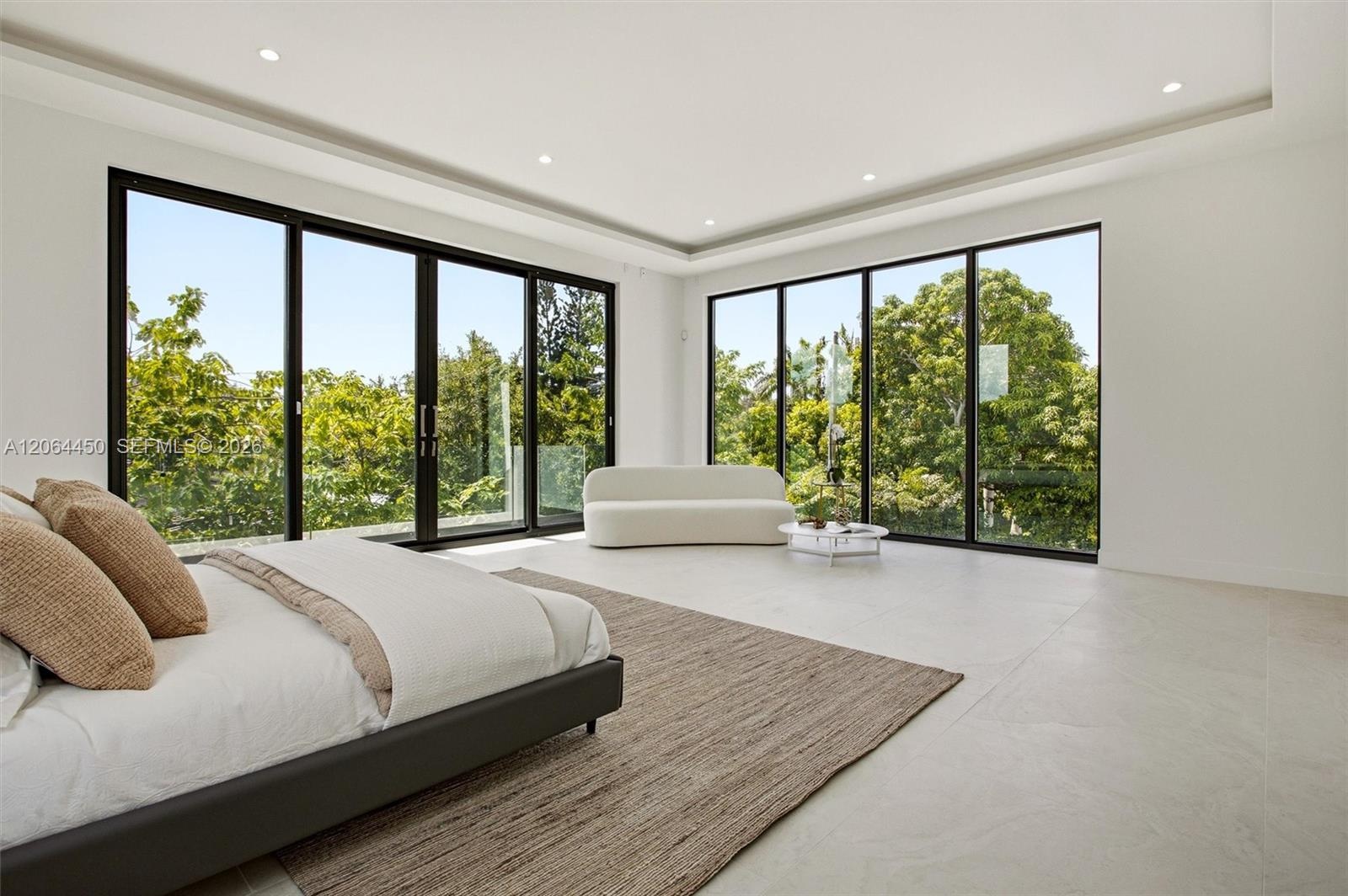 Open-concept interior featuring large-format tile flooring, recessed ceiling lighting, tray ceiling details, and floor-to-ceiling glass sliding doors 