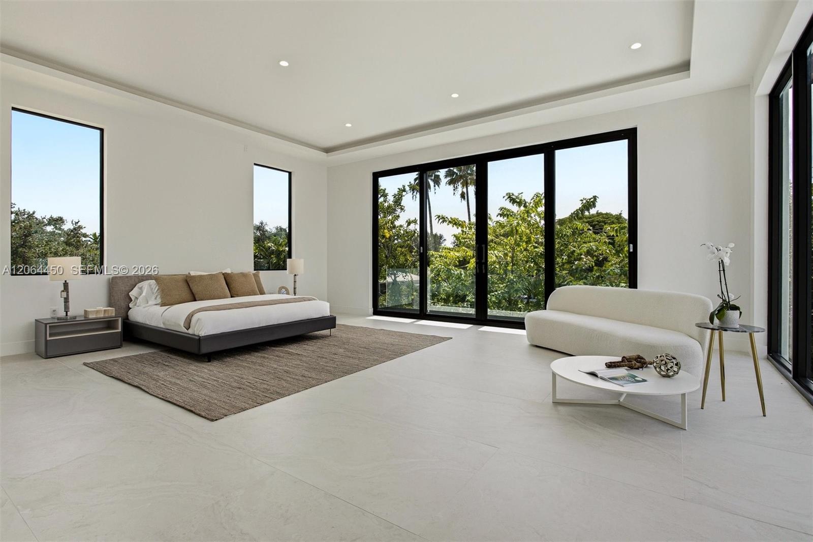 Large-format tile flooring, recessed ceiling lighting, tray ceiling, and expansive glass sliding doors with black frames