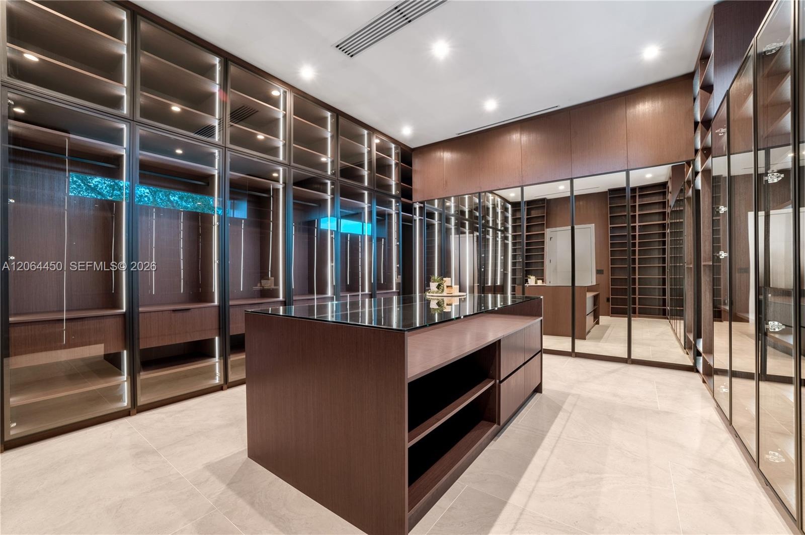 Boutique style closet with glass front cabinetry, lighting, and a center island