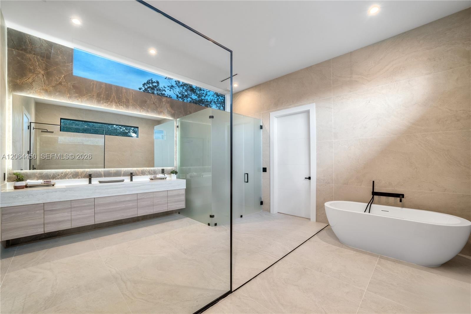 Primary bath with a freestanding soaking tub, dual vanities, and walk in shower