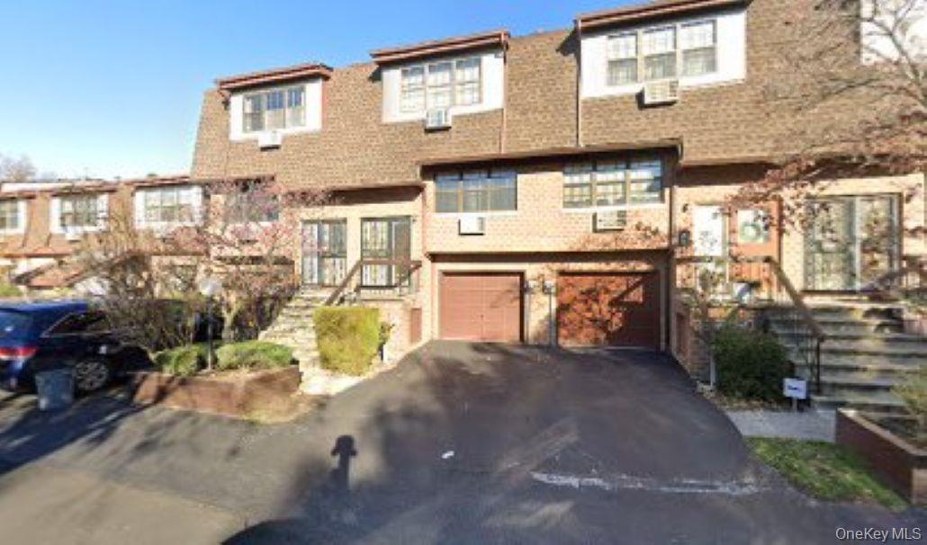 Multi-level brick exterior featuring multi-pane windows, shingled roofing, and attached garage