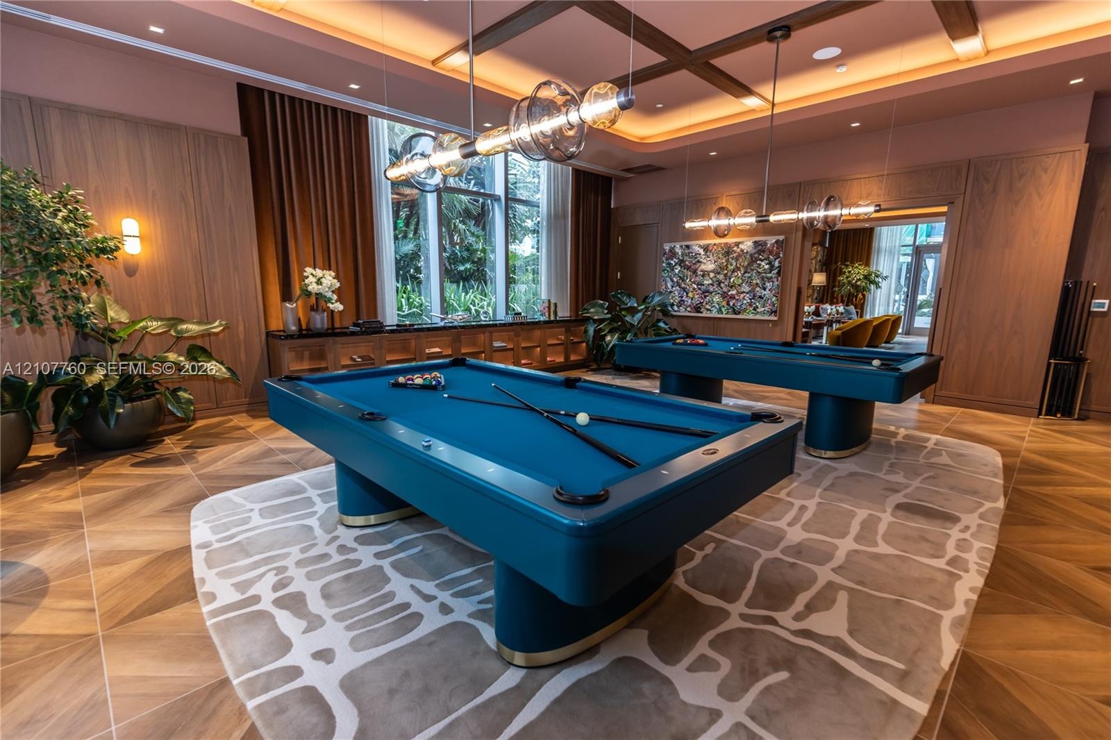 Wood-finish flooring, coffered ceiling with recessed lighting, floor-to-ceiling wood wall paneling, built-in cabinetry, and multi-light linear pendant