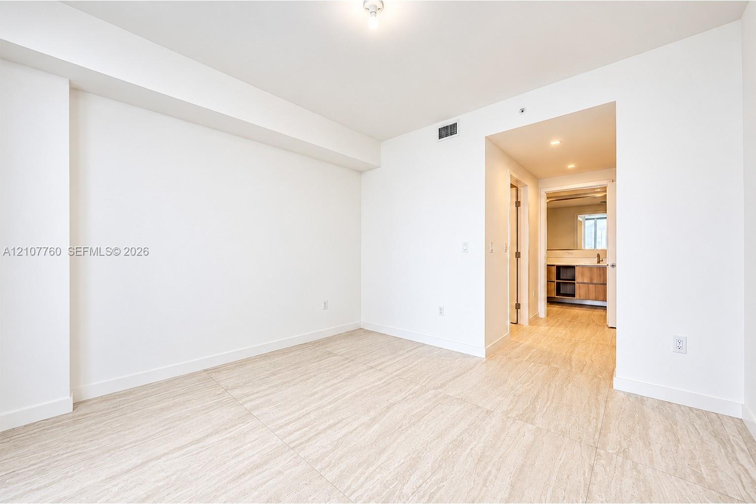 Neutral-toned tile flooring, smooth wall finishes, and recessed lighting
