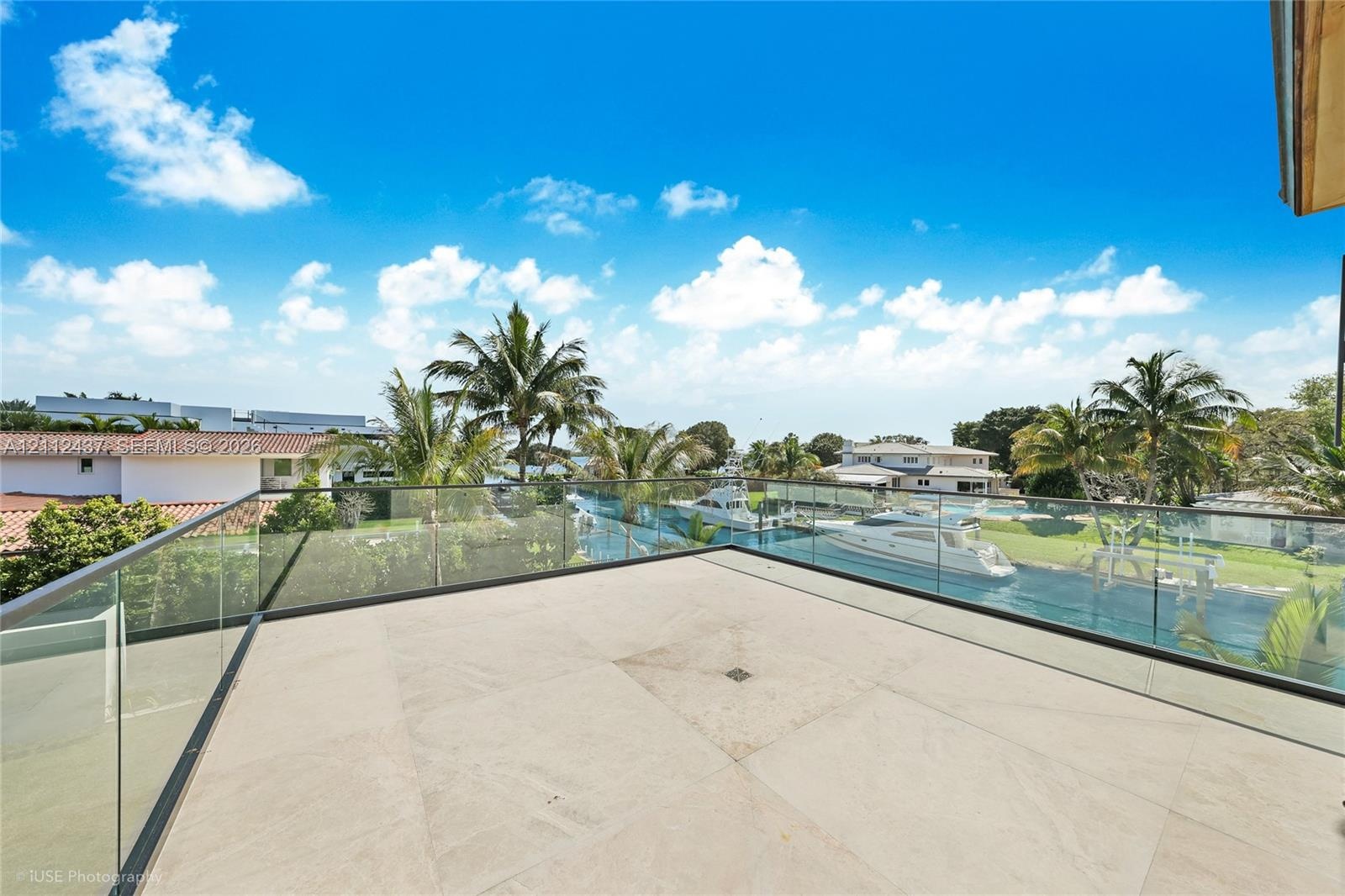 Open-air terrace featuring large-format stone tile flooring and a seamless glass panel railing