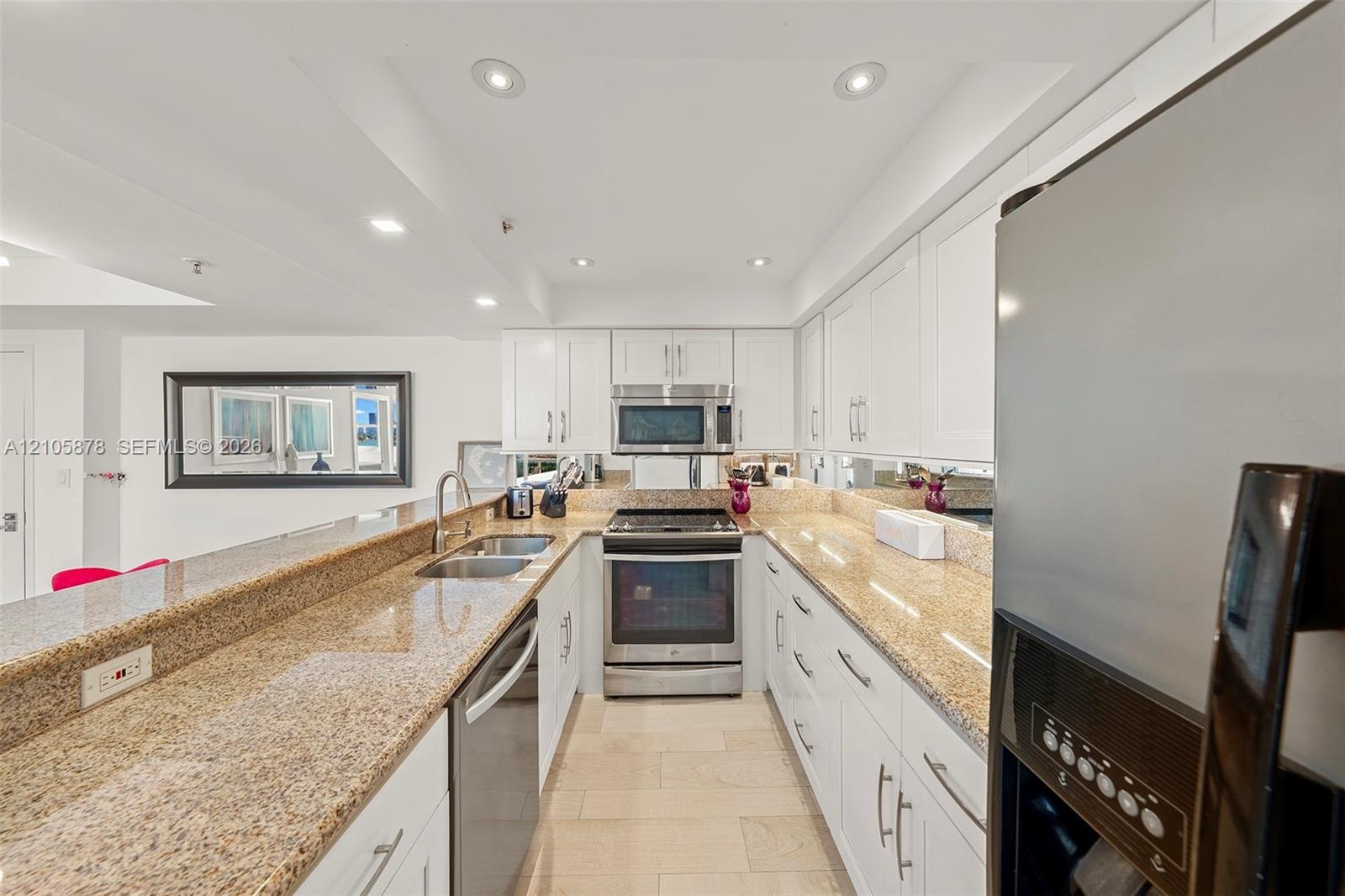 Kitchen featuring white cabinetry, stone countertops, stainless steel appliances, a double-basin sink, and tile flooring