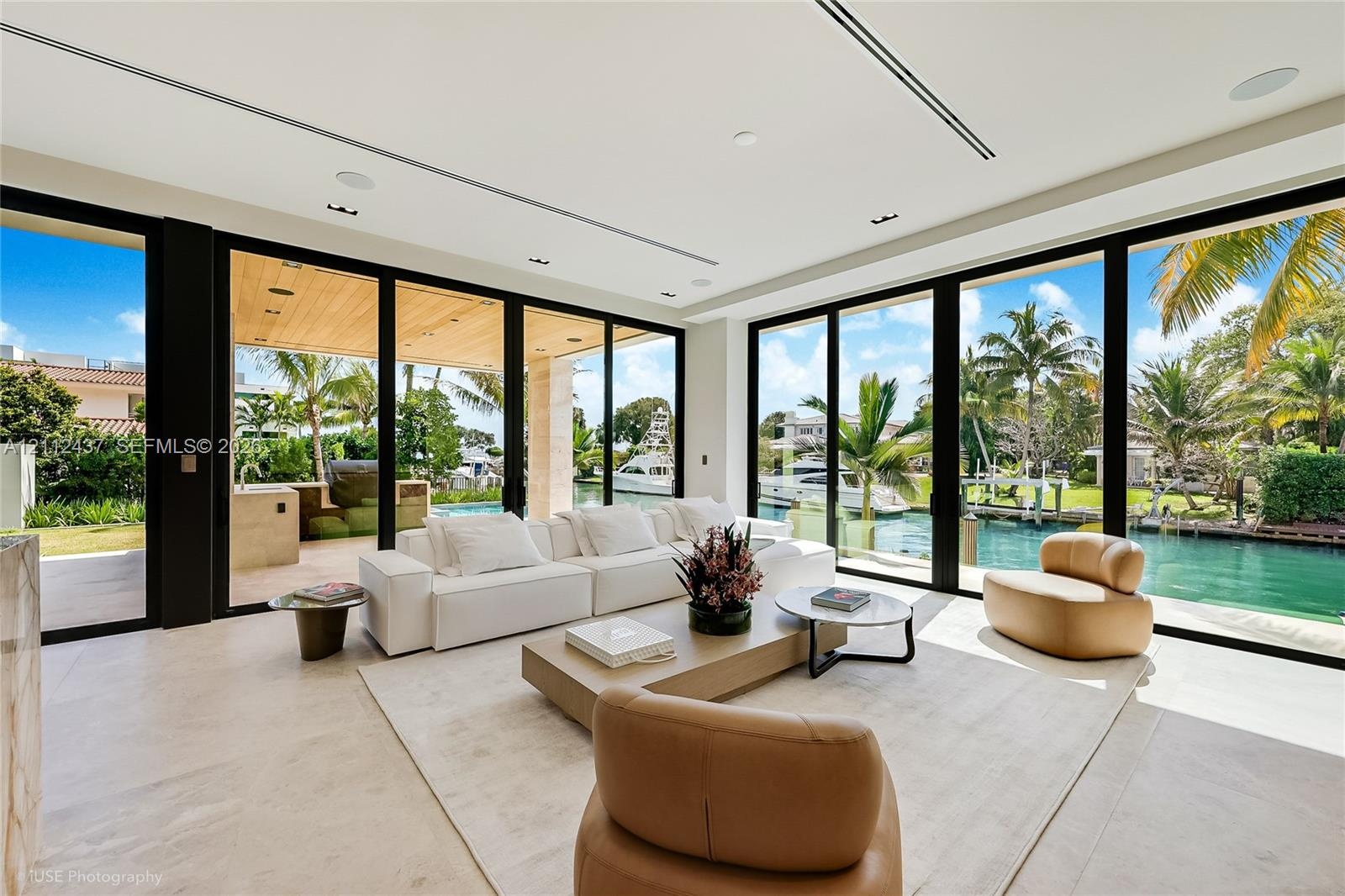 Living area featuring floor-to-ceiling glass sliding doors, recessed lighting, built-in light-tone cabinetry, and natural stone flooring
