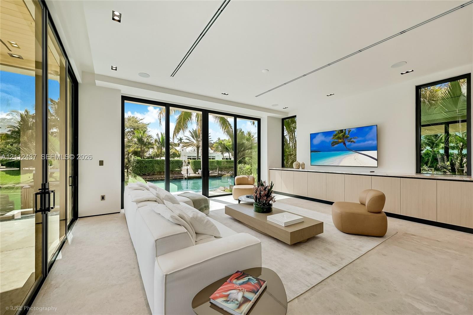 Custom light-finish cabinetry, natural stone backsplash and range hood surround, integrated stainless steel appliances, stone slab countertop, and rec