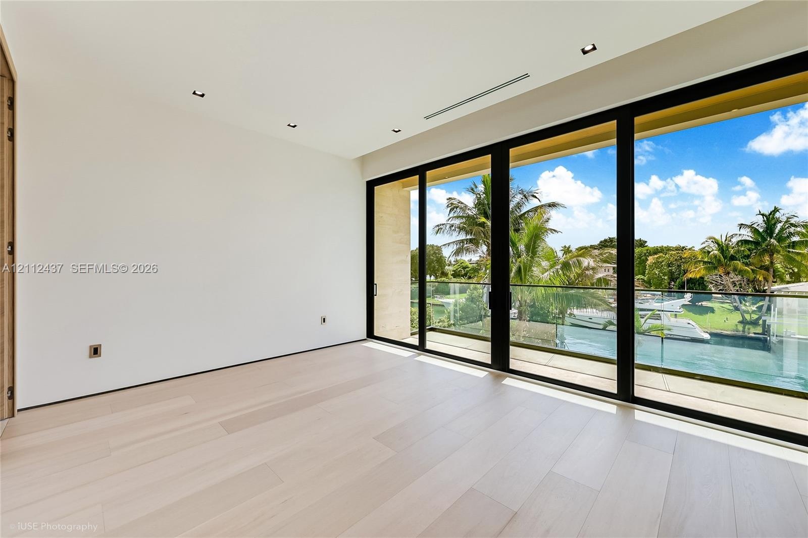 Light-filled room featuring wood-finish flooring, recessed lighting, and floor-to-ceiling multi-panel sliding glass doors with access to a balcony wit