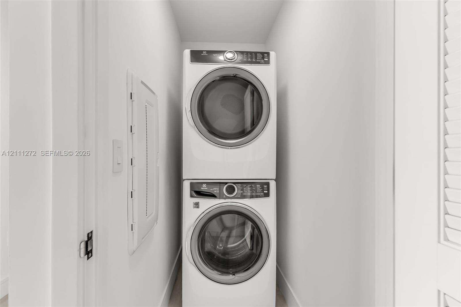 Stacked white front-load washer and dryer unit with digital control panels