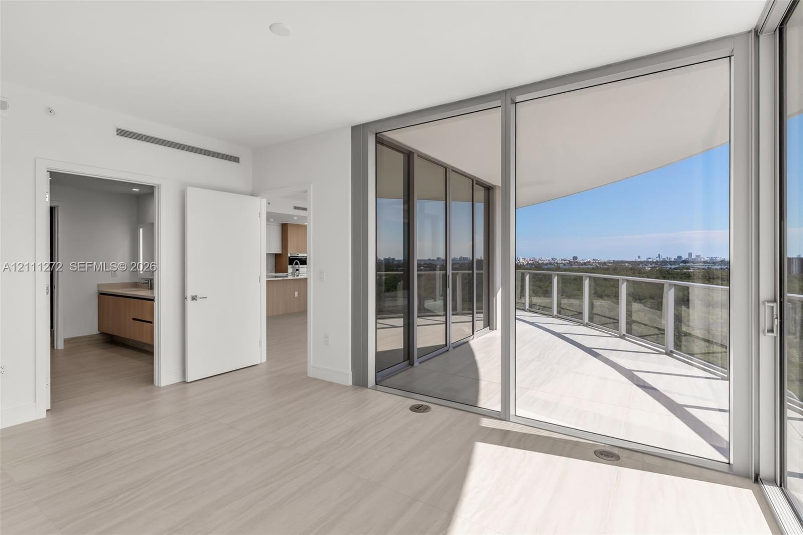Floor-to-ceiling glass walls, expansive covered balcony, wood-finish flooring, and recessed ceiling lighting
