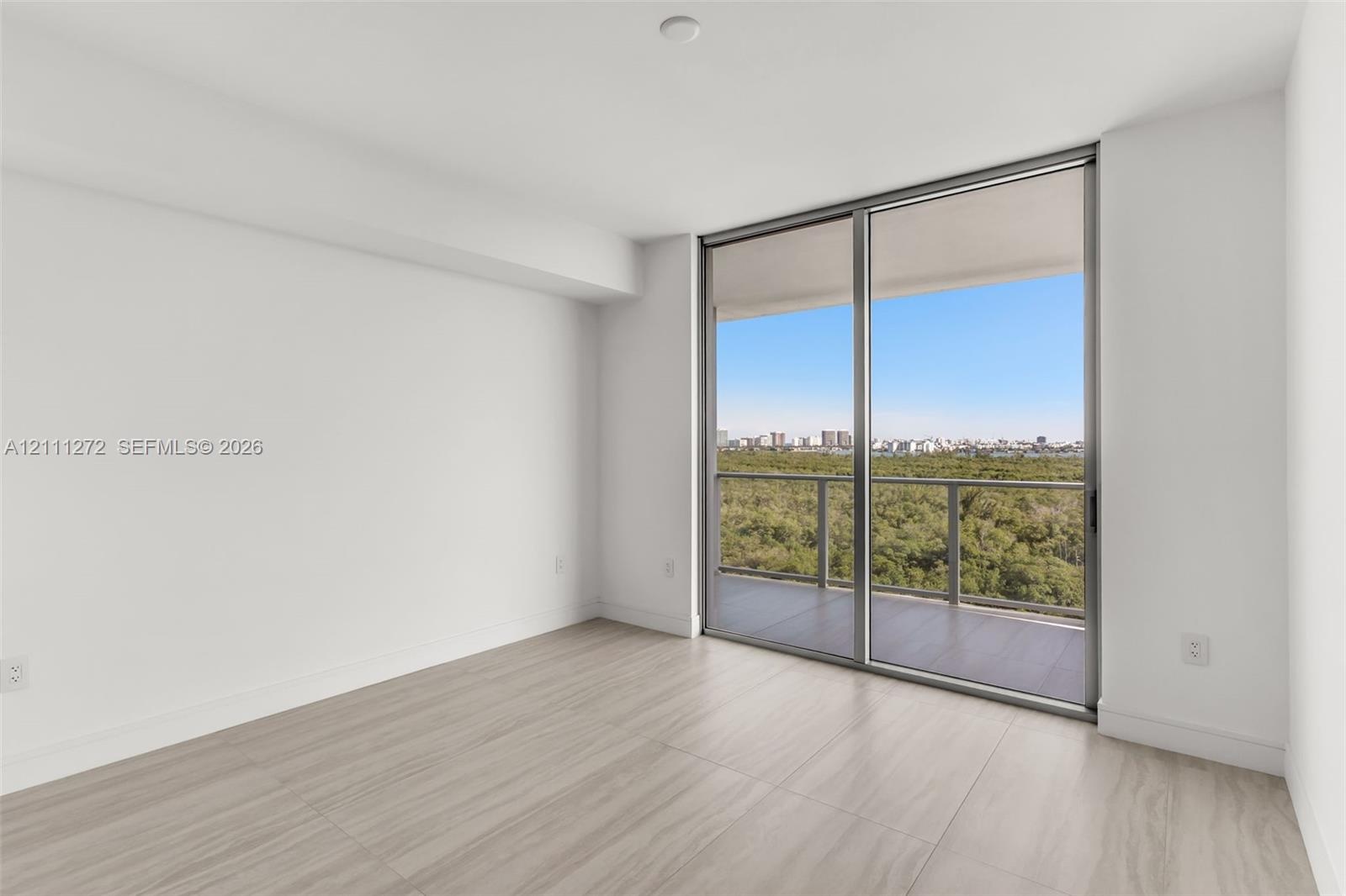 Light-filled room featuring wood-finish flooring, floor-to-ceiling sliding glass doors, and a private balcony with metal railings