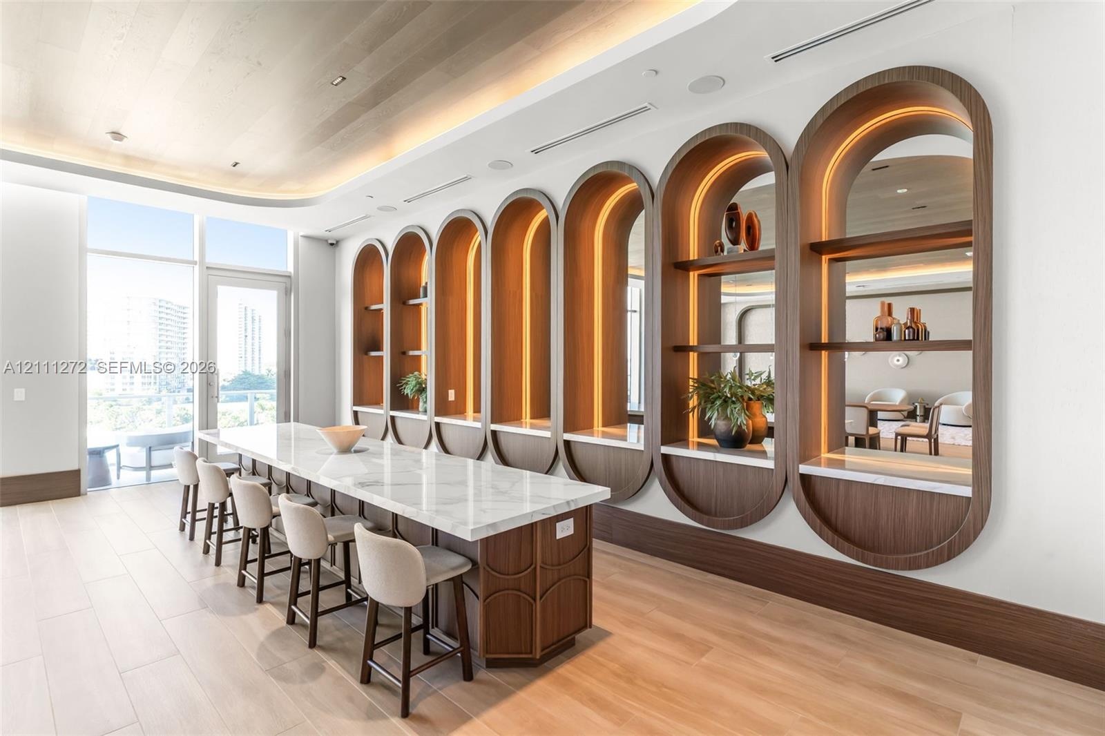 Extended island featuring a stone-style countertop, integrated arch-framed shelving with recessed lighting, mirrored backings, wood-finish flooring, a