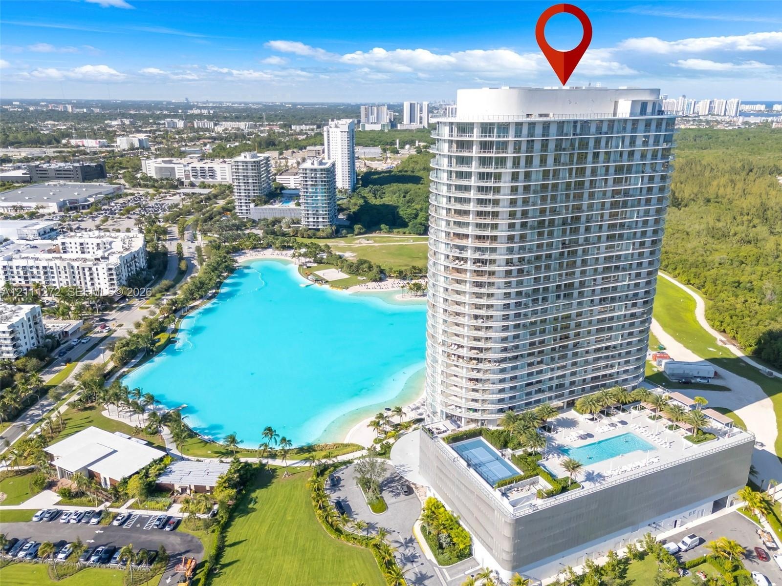 High-rise residential tower featuring a multi-story glass facade, a private elevated outdoor swimming pool, and dedicated hardscaped parking structure