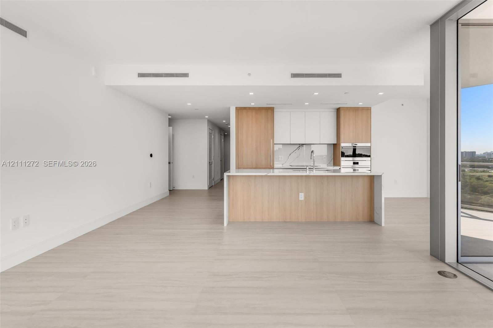 Kitchen featuring two-tone wood-finish and white cabinetry, stone-finish backsplash, built-in stainless steel appliances, and a central island with a 
