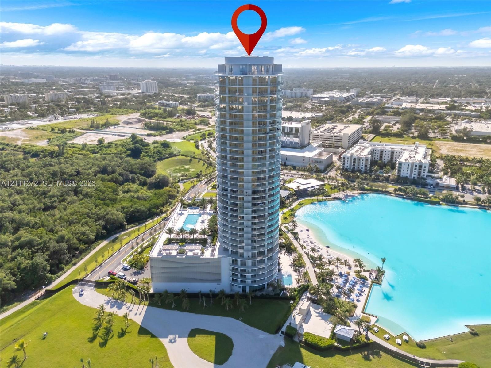 High-rise tower featuring wrap-around balconies, an outdoor swimming pool, and proximity to a large-scale lagoon