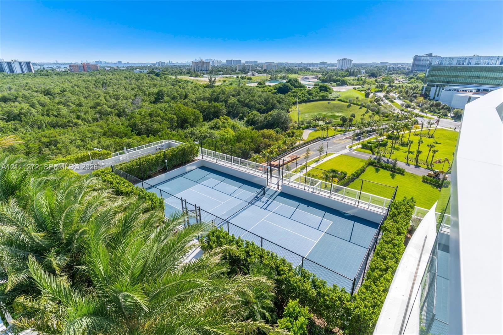 Hard-surface tennis court featuring perimeter chain-link fencing and lush vegetation border