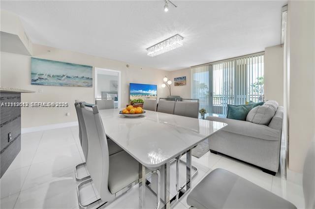 Open-concept living space featuring high-gloss tile flooring, floor-to-ceiling sliding glass doors, and a rectangular, modern tiered crystal ceiling f
