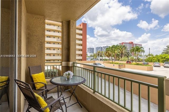 Covered balcony featuring textured stucco walls, painted metal railing, and concrete flooring