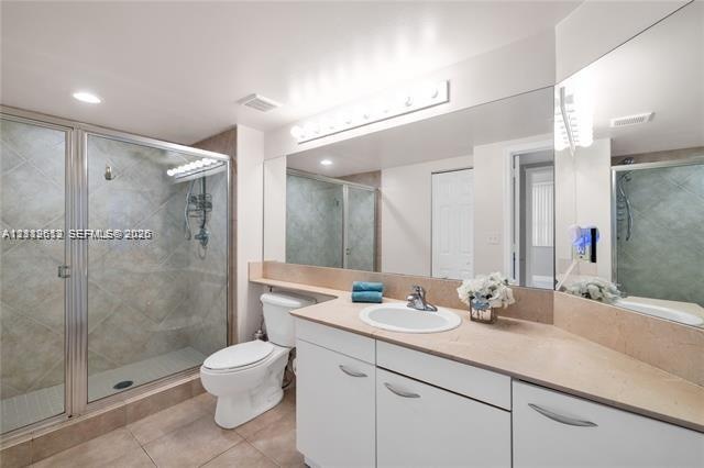Full-width vanity with a neutral solid-surface countertop and recessed basin, glass-enclosed shower with tile surround, and expansive wall-to-wall mir