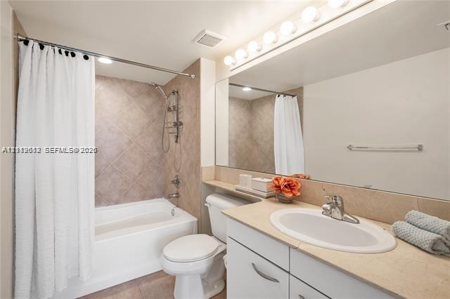 Bathroom featuring a recessed tub with a tile surround, a built-in vanity with a solid-surface countertop, an integrated oval sink, and a full-width w