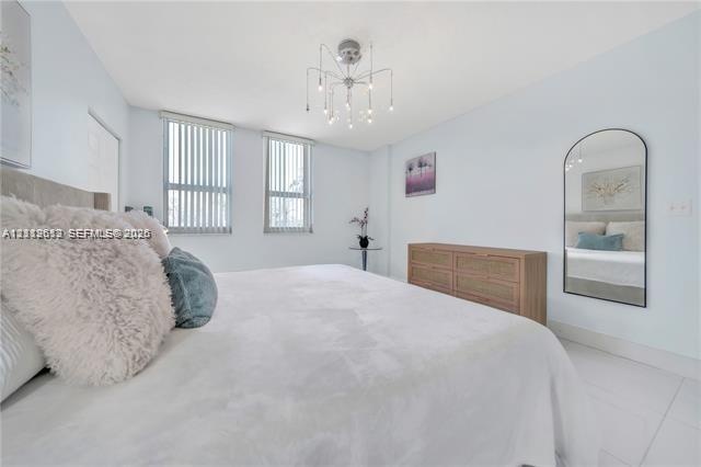 Bright room featuring light-toned flooring, multi-pane windows with vertical blinds, a contemporary sputnik-style chandelier, and an arched wall-mount
