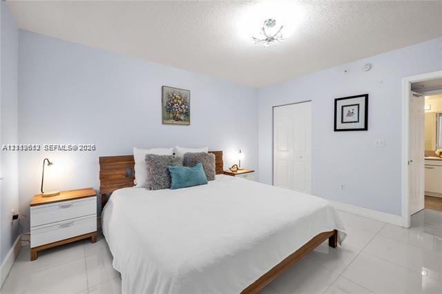 Spacious room featuring polished white tile flooring, ceiling-mounted light fixture, and a reach-in closet with double doors