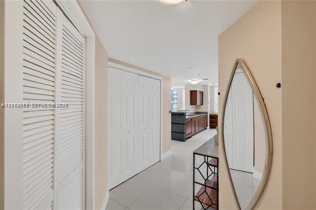 Interior area featuring high-gloss tile flooring, white bi-fold closet doors, and recessed ceiling lighting