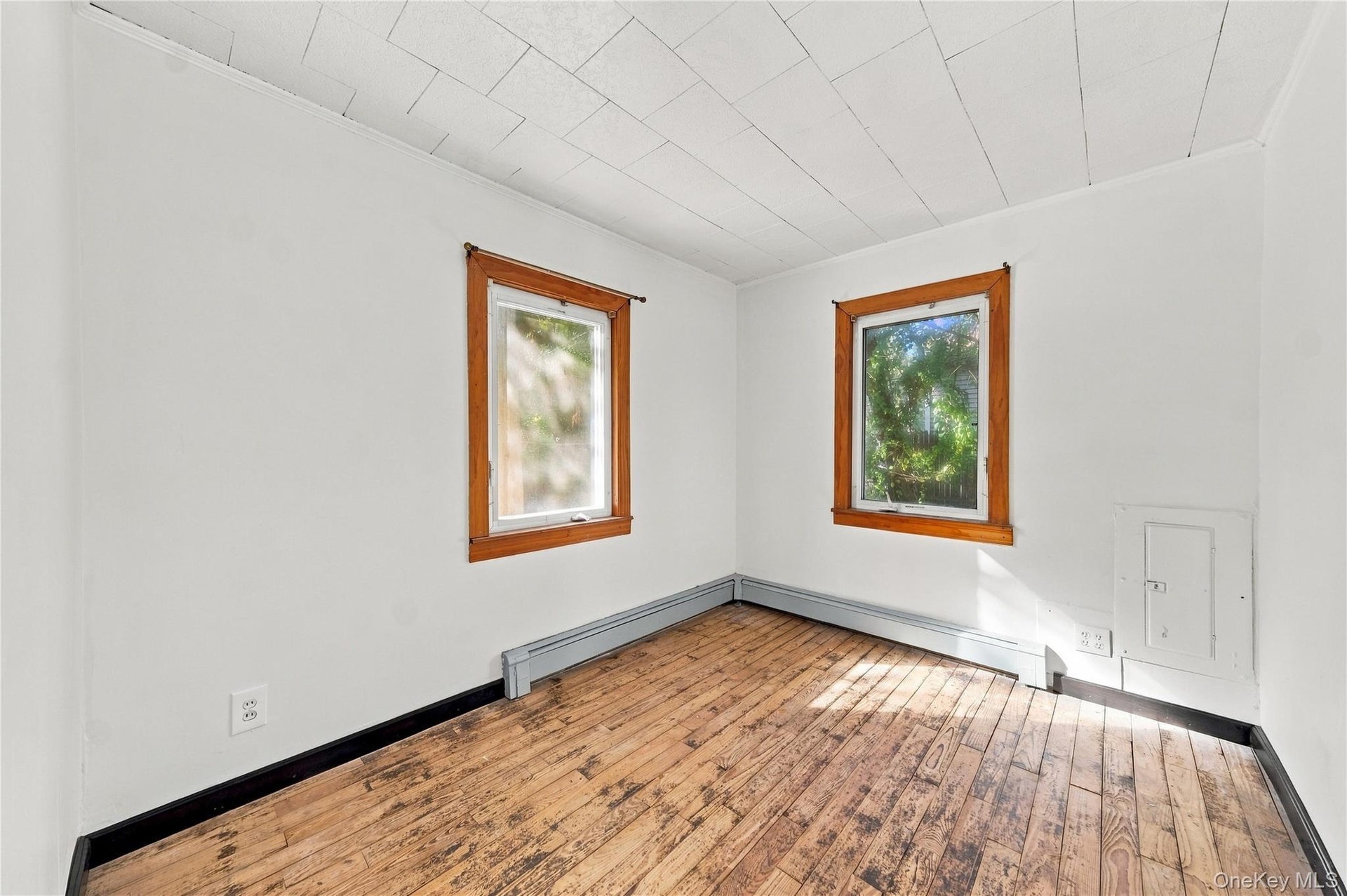 Wood-finish flooring, two windows with natural wood trim, freshly painted