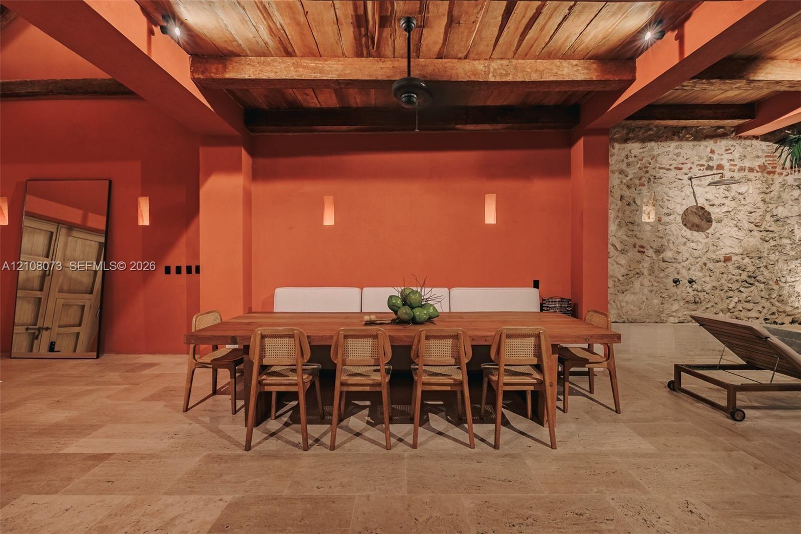 Exposed timber ceiling beams, stone masonry accent wall, stone-finish flooring, and recessed ceiling lighting