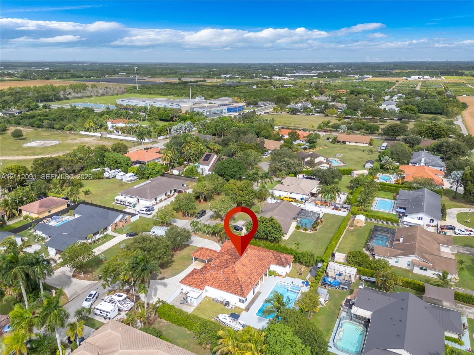 Aerial perspective featuring a single-story residence with a multi-hipped terracotta tile roof, an in-ground swimming pool, concrete paved patio area,
