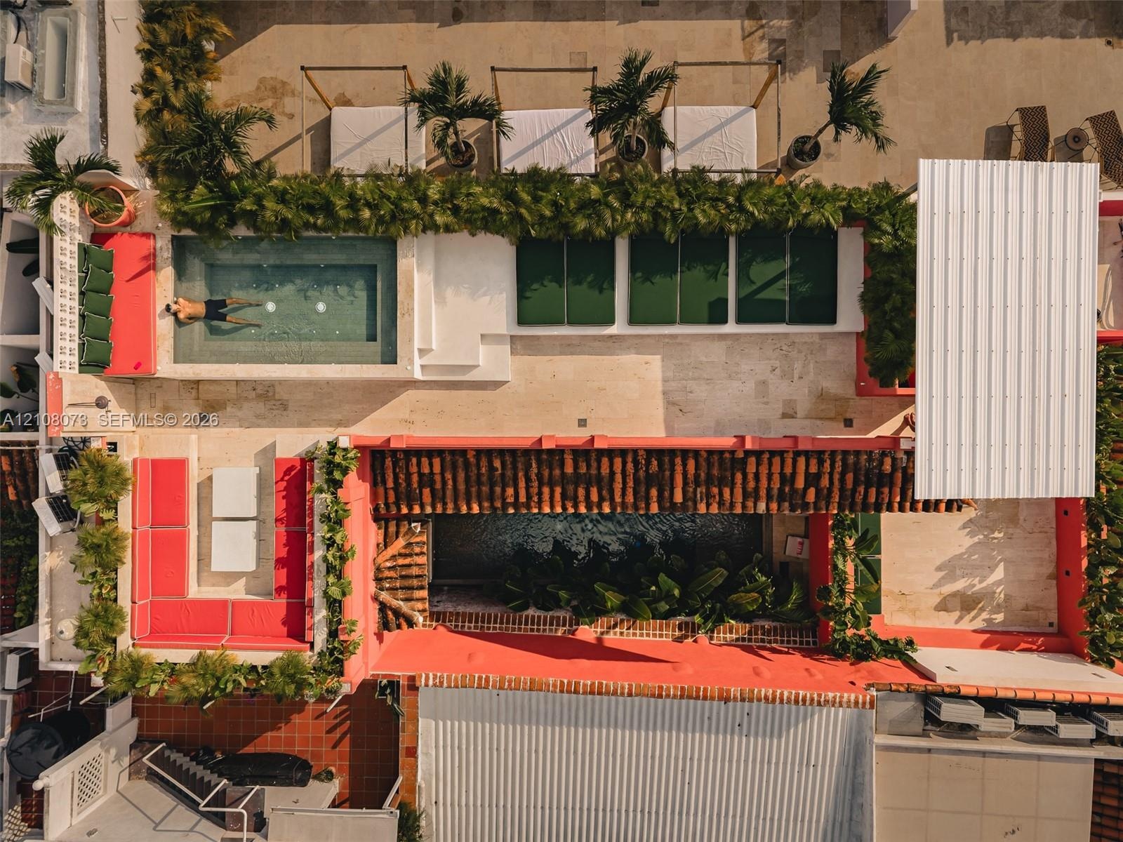 Rooftop terrace featuring a tiled plunge pool, stone hardscaping, built-in masonry bench seating, corrugated metal roofing, and integrated landscaping