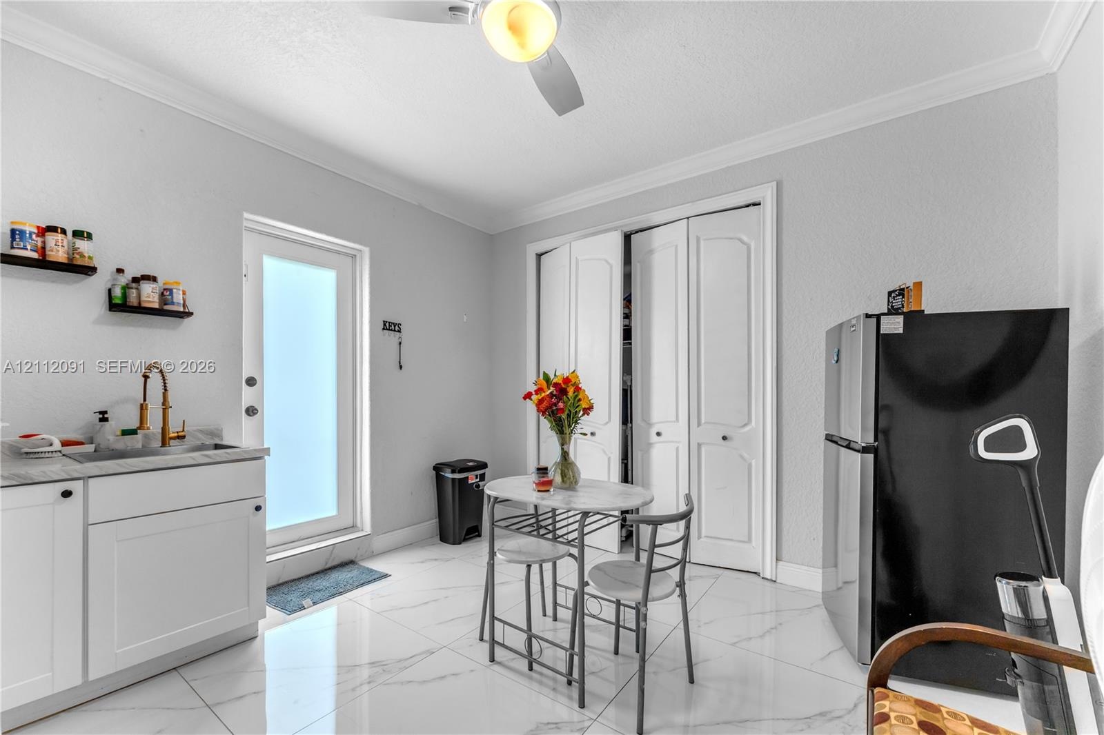 Polished tile flooring, built-in lower cabinetry with stone-finish countertops, undermount sink with brass-finish faucet, bi-fold closet doors, and ex