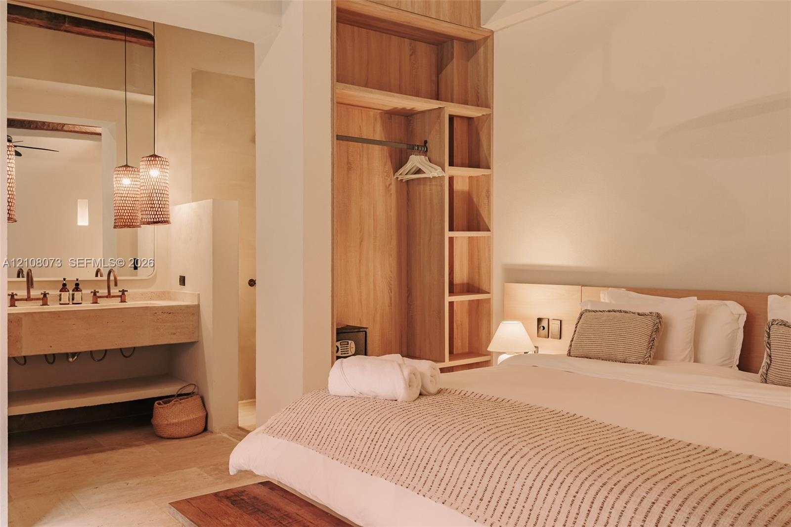Built-in wood shelving, custom floor-to-ceiling wardrobe, stone-surfaced vanity with dual basins, and pendant lighting