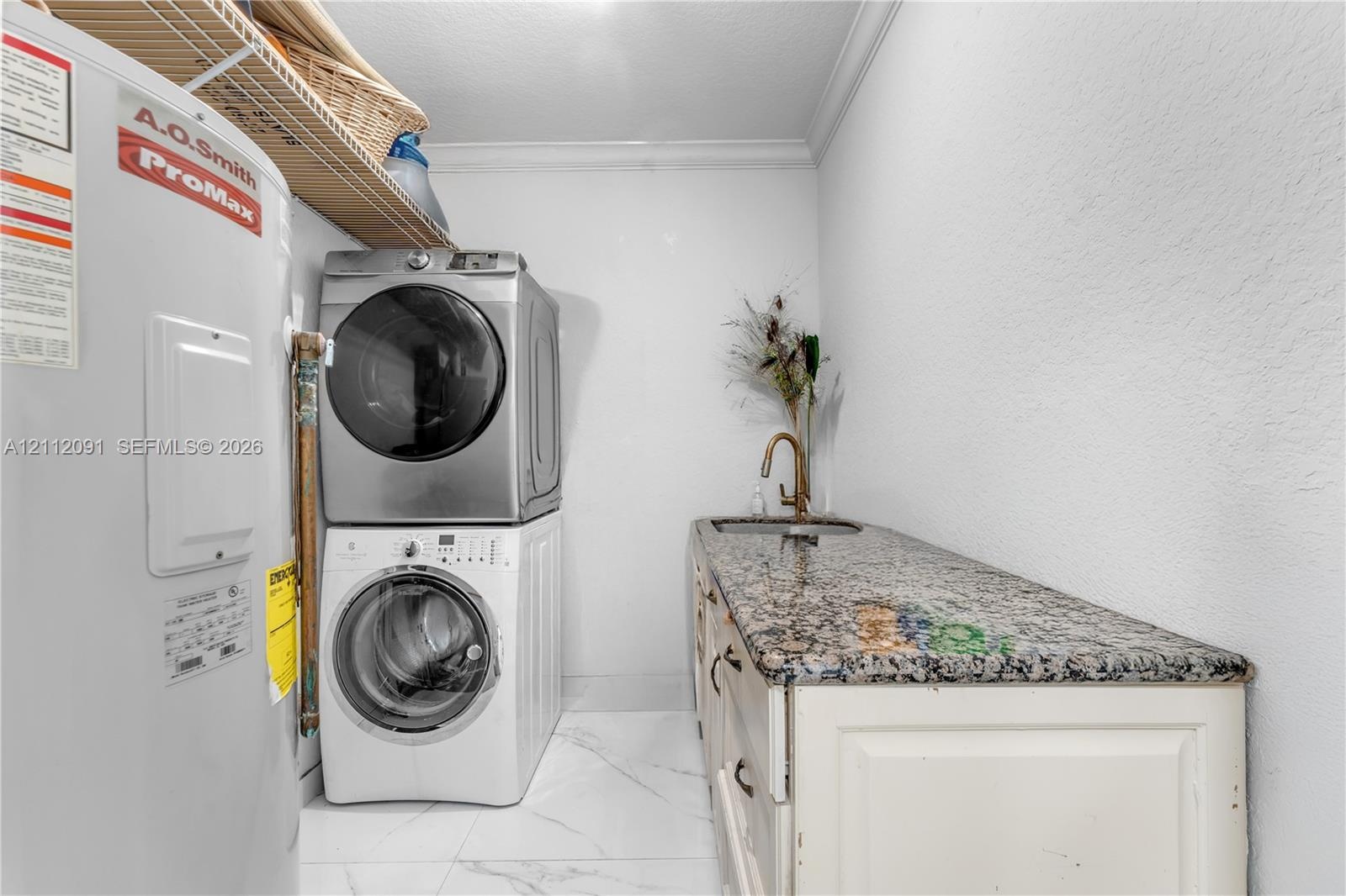 Utility area featuring a built-in cabinet with stone-finish countertop, undermount sink, gooseneck faucet, and white tile flooring