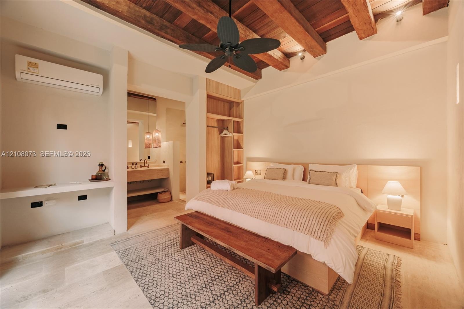 Exposed timber ceiling beams, integrated wood-finish wardrobe cabinetry, neutral stone-finish flooring, and wall-mounted ductless climate control unit
