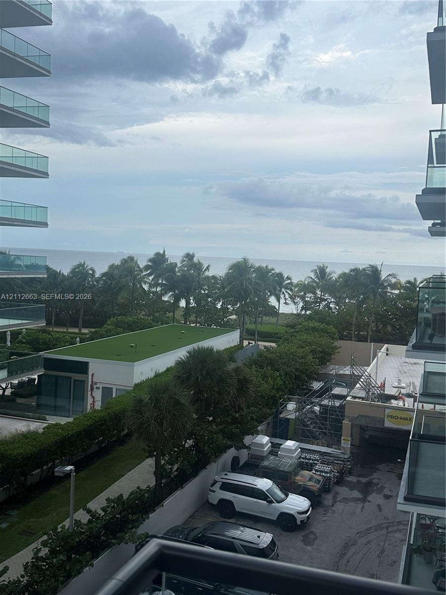 Balcony featuring glass railings and an expansive horizon line including ocean and coastal greenery