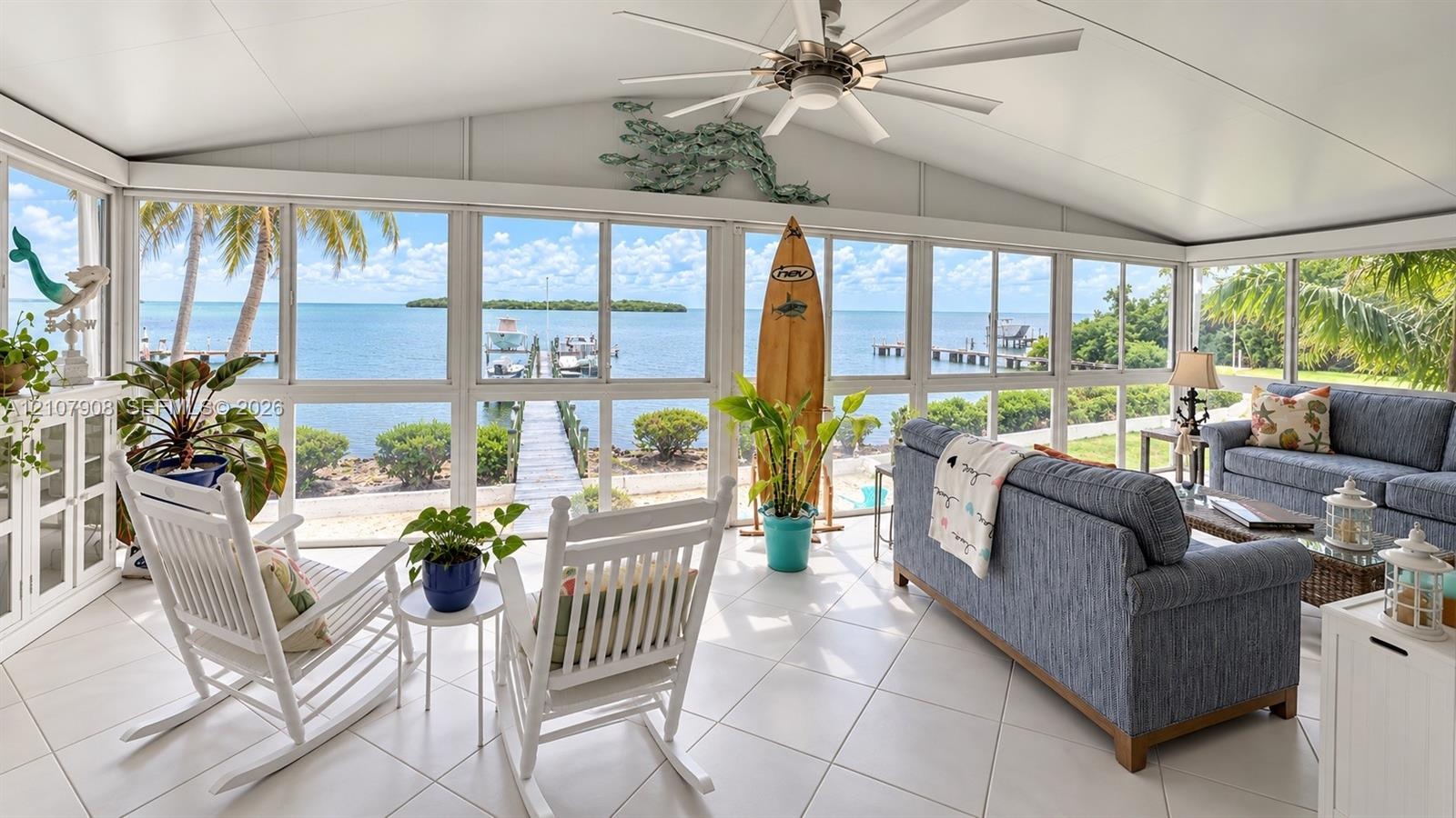 Screened lanai featuring large-format ceramic tile flooring, a vaulted ceiling with a central paddle fan, and an expansive wall of floor-to-ceiling wi
