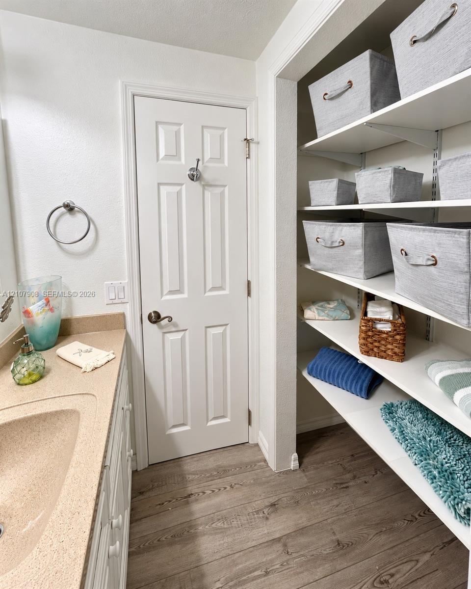 Solid surface vanity with an integrated basin, wood-finish flooring, and built-in adjustable shelving