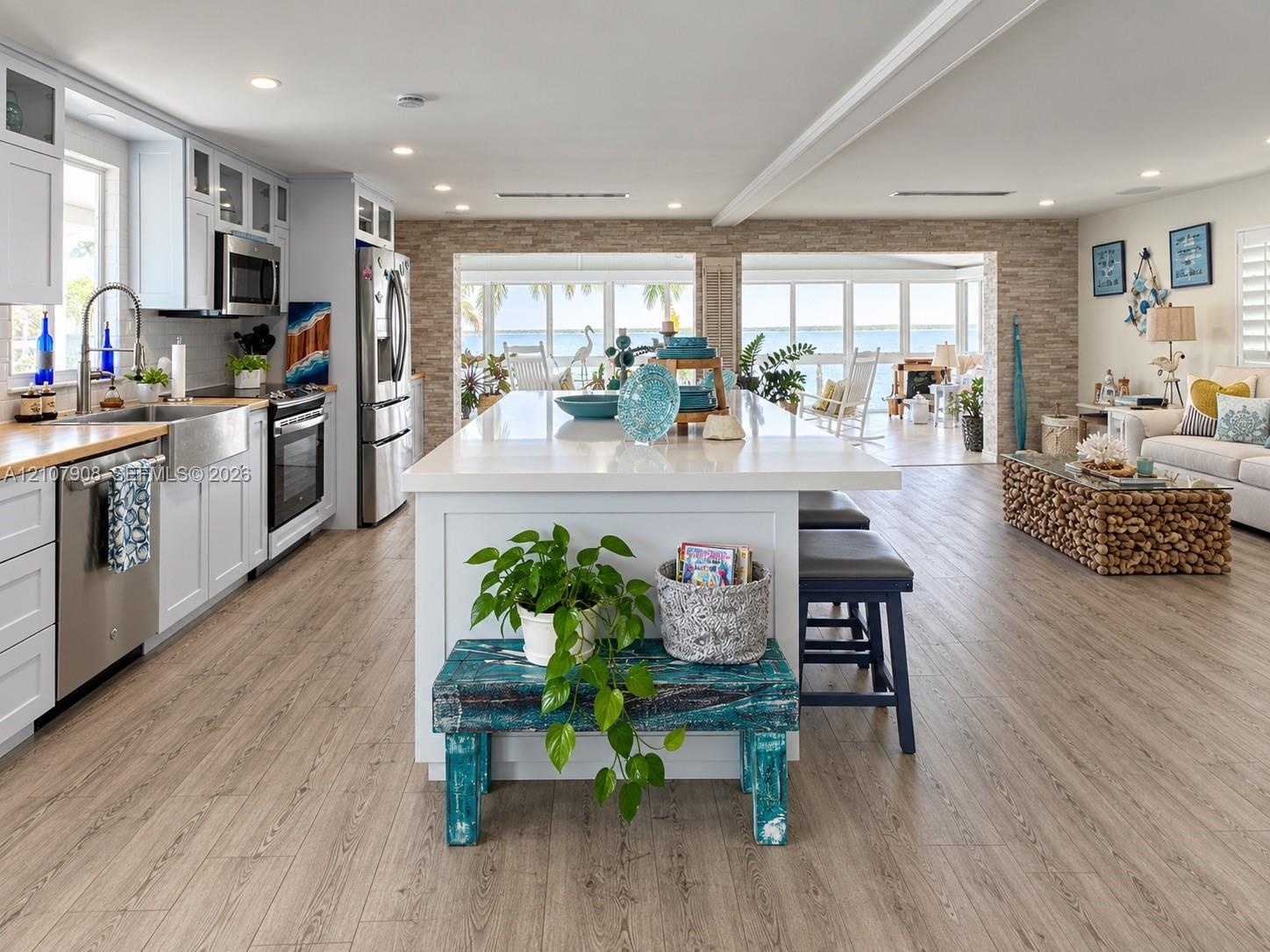 Kitchen featuring white shaker-style cabinetry, stainless steel appliances, a farmhouse sink, a central island with a solid surface countertop, and wo